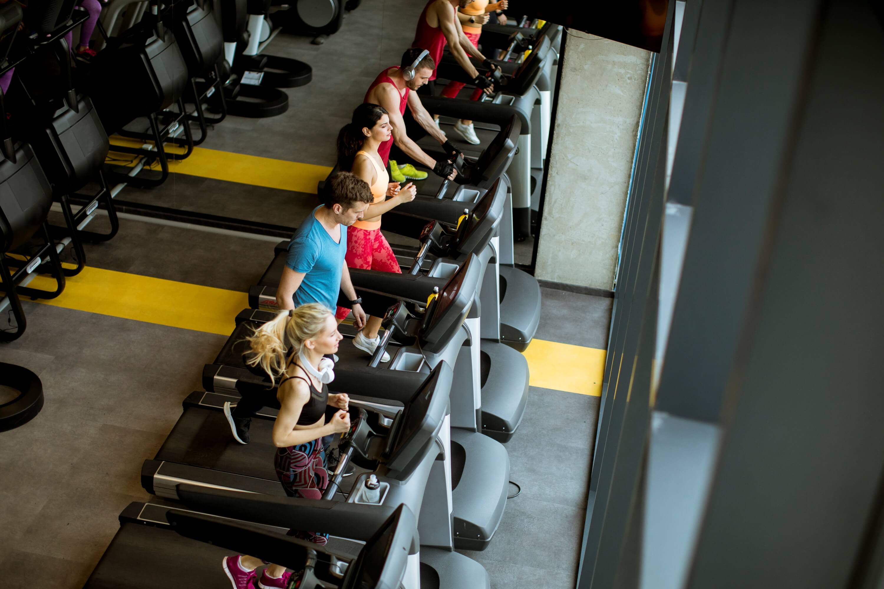 Modern gym floor with equipment, member scanning QR code on exercise machine, bright motivating environment.